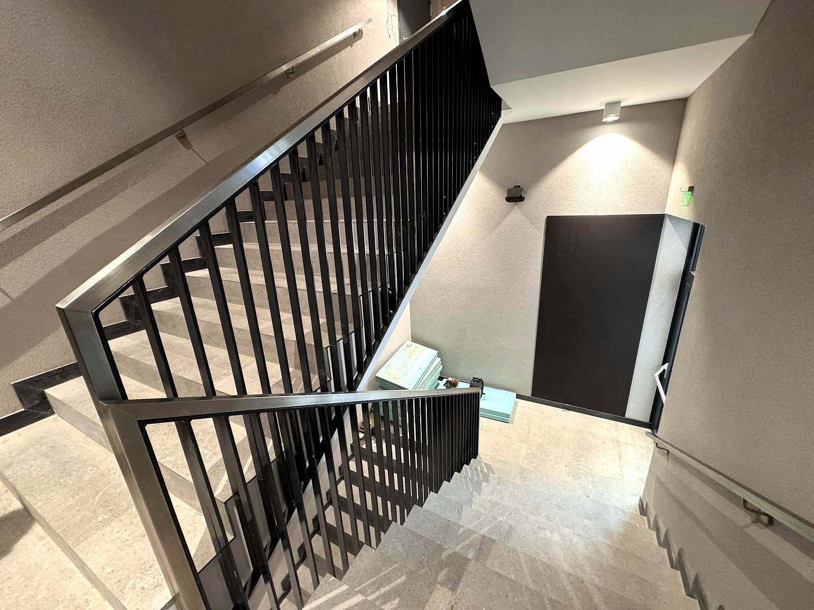 Modern interior black metal staircase railing with vertical infill and stainless steel handrail, custom fabrication and installation in Praktiker - Sofia, Bulgaria